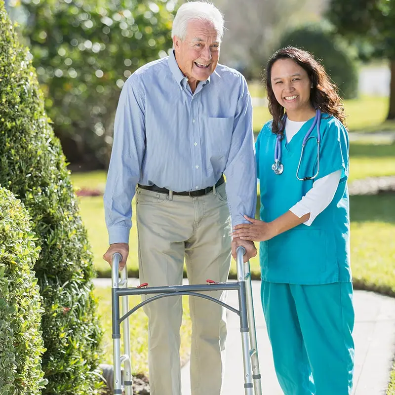 Tall walkers for seniors are available on retail websites like Amazon. Here a happy elderly senior is taking a stroll in the park with the help of a walker. A doctor is standing beside him.